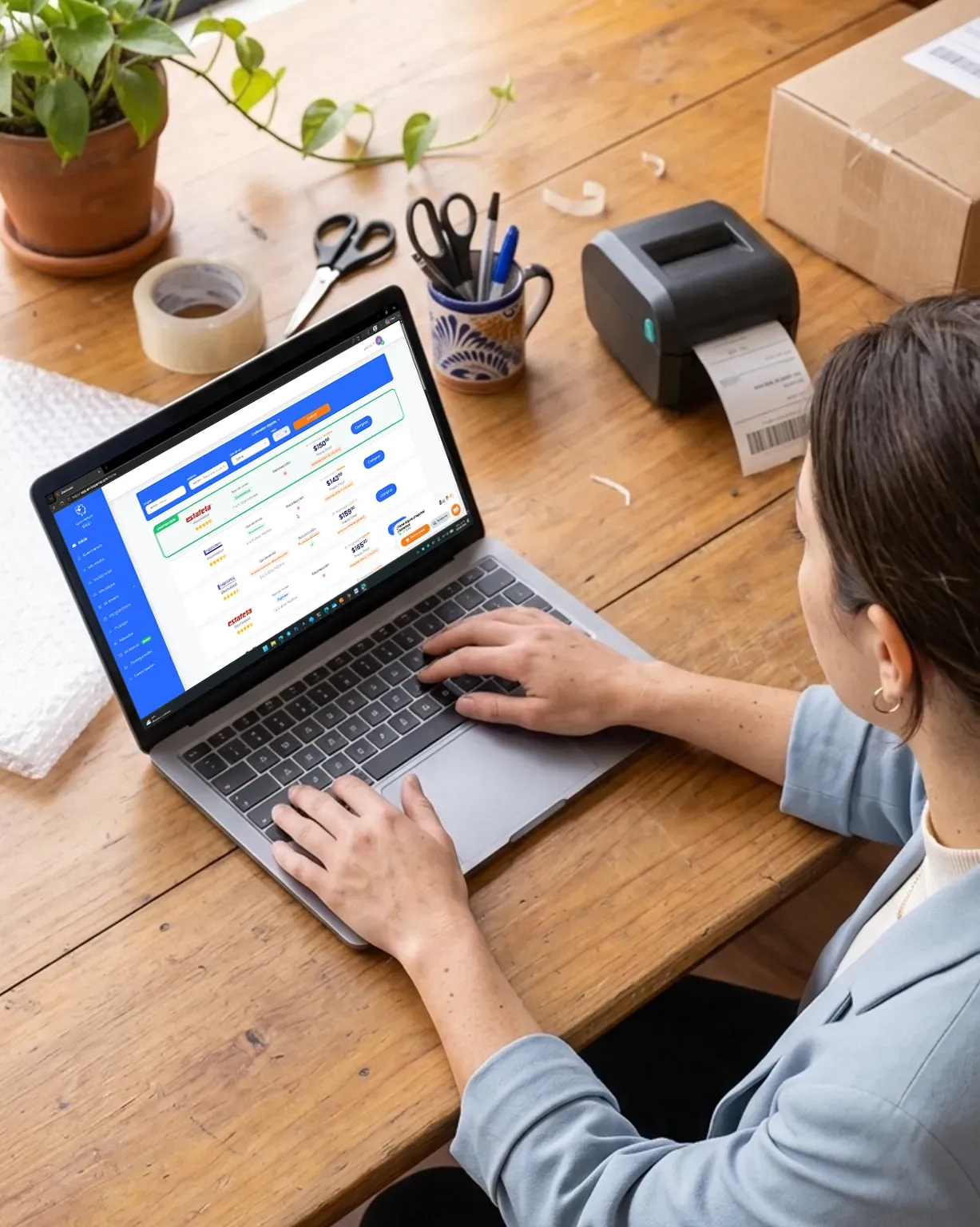 Emprendedora comparando tarifas de paqueterías en la plataforma desde su laptop, junto a su impresora de guías